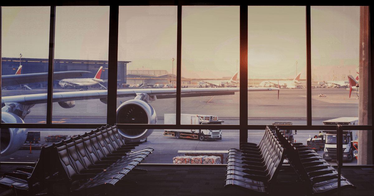 View from an airport window of a commercial airplane parked at the gate before departure.
